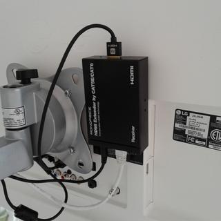 Monoprice HDMI extender attached to back of wall-mounted TV with velcro.